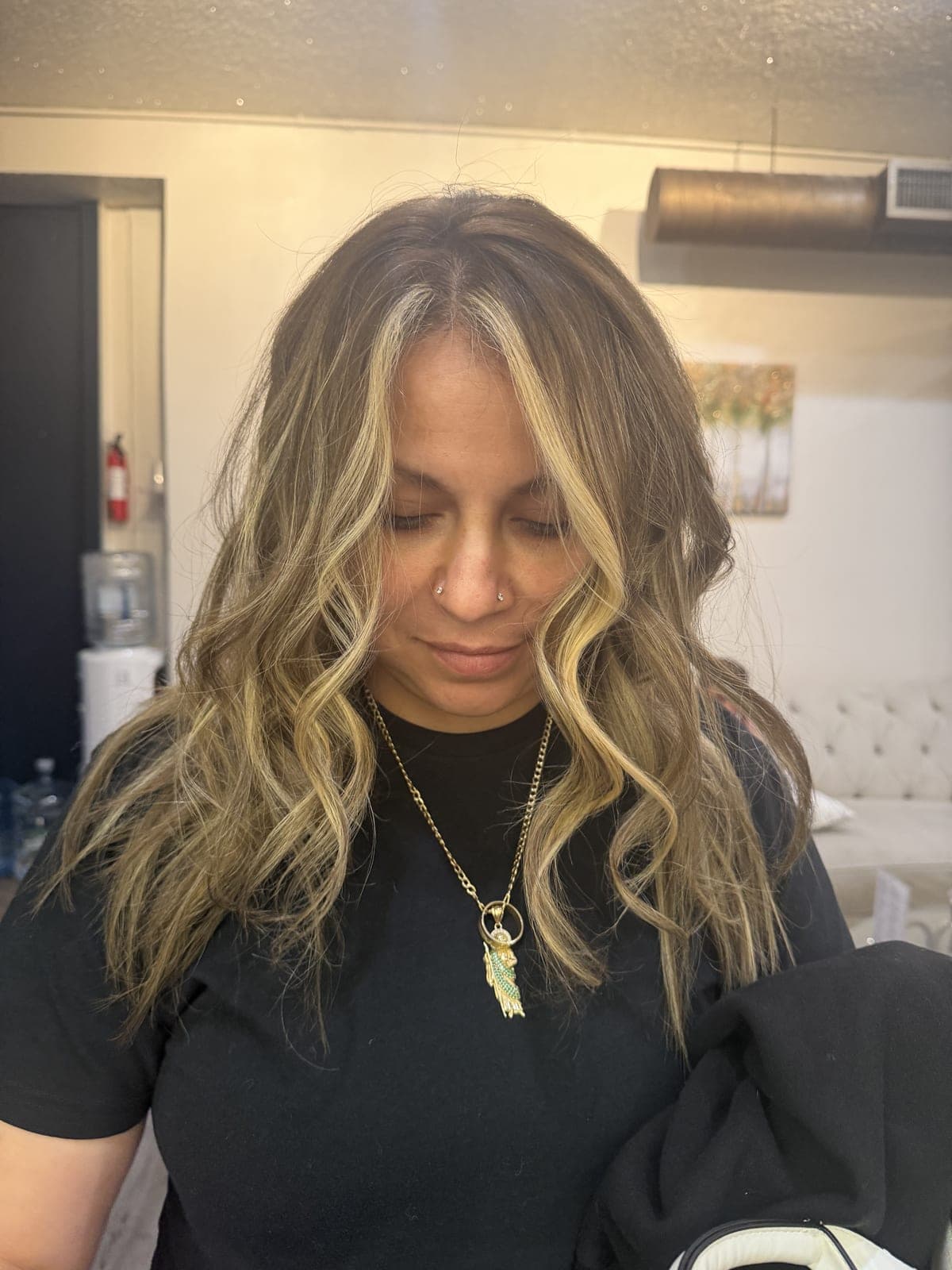 Client seated in the salon chair with long blonde balayage waves framing her face