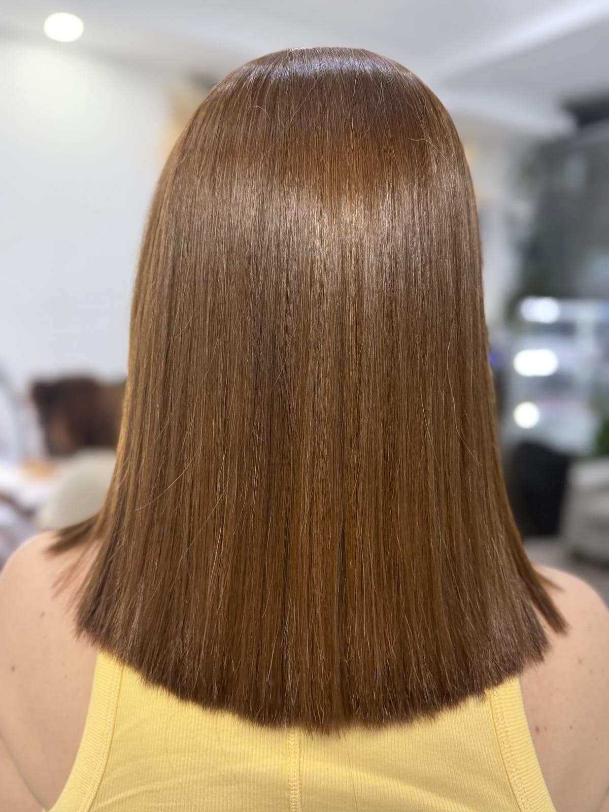 Glossy warm-brown single-process color on a straight blunt cut, shining under salon light