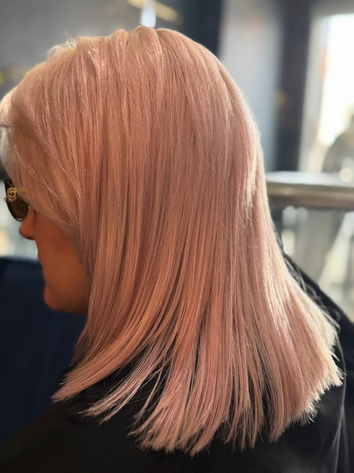 Rose-gold blonde color on straight shoulder-length hair, photographed outdoors in daylight