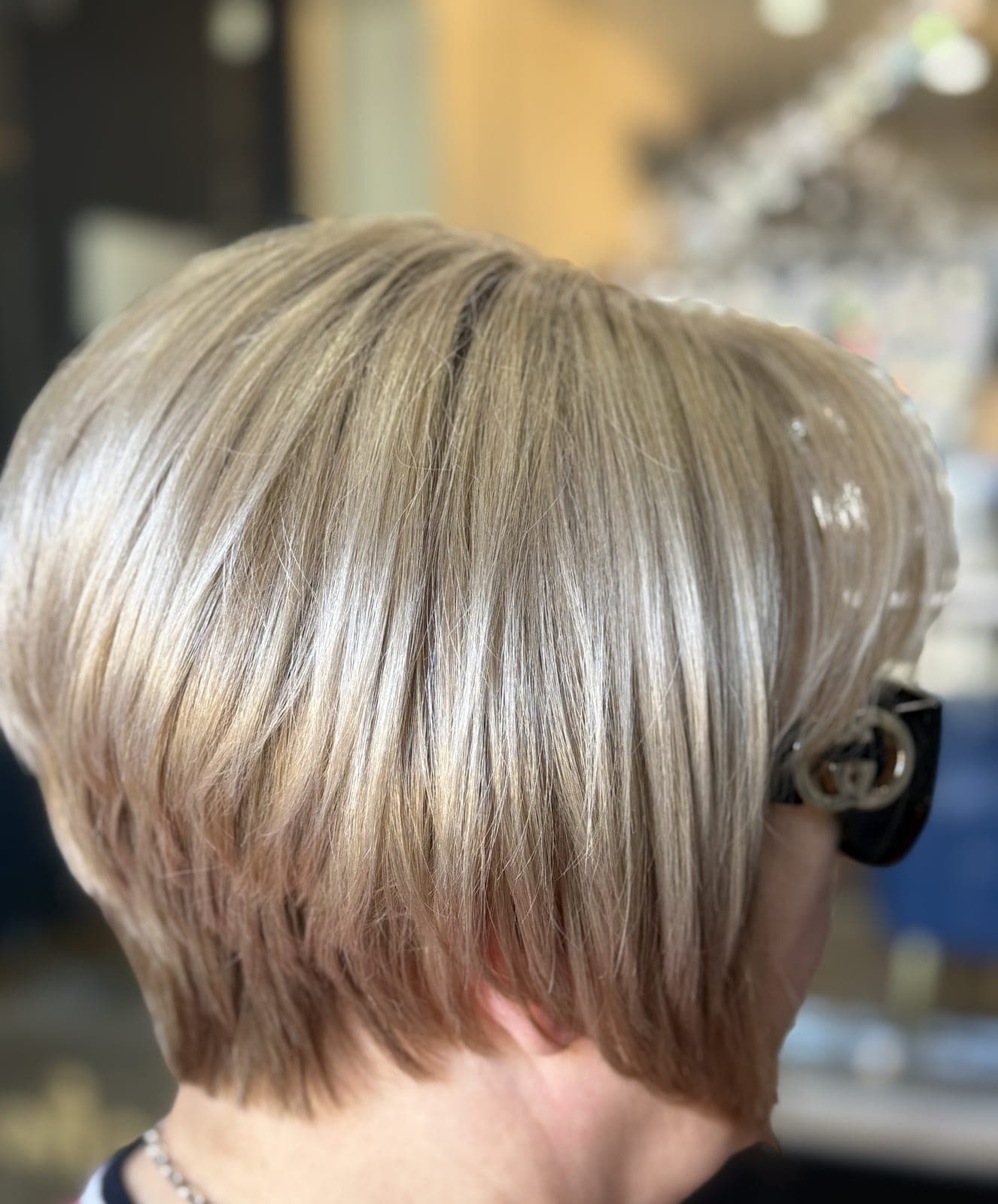 Short silver-ash cut on a mature client, blended and softly layered, seen from the side