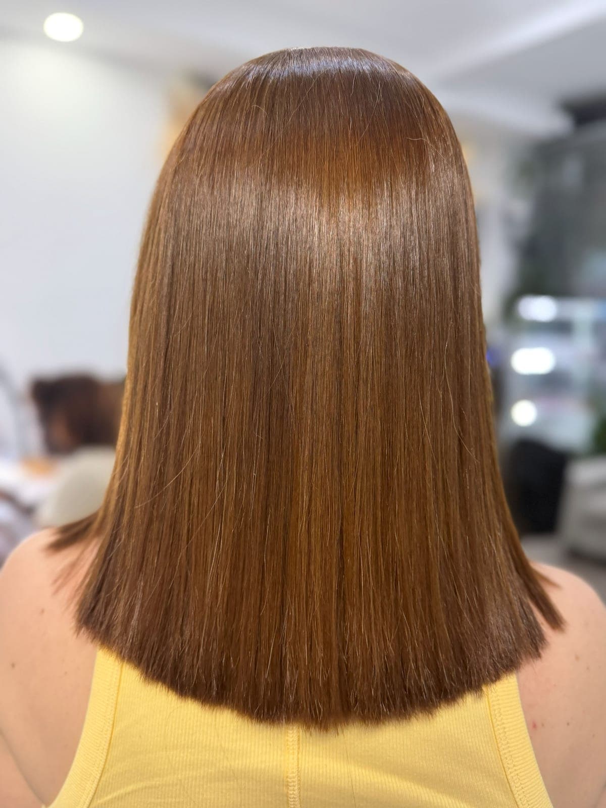 Even copper tone on a blunt shoulder-length cut after colour correction, seen from the back