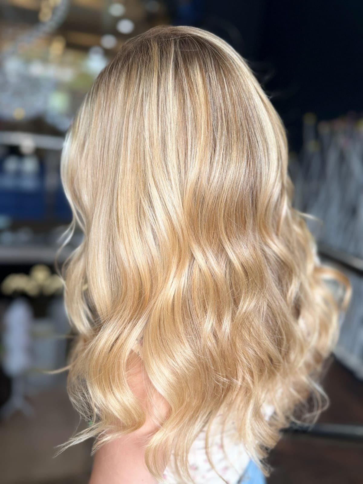 Bright blonde colour on long hair styled in loose waves, seen from the back