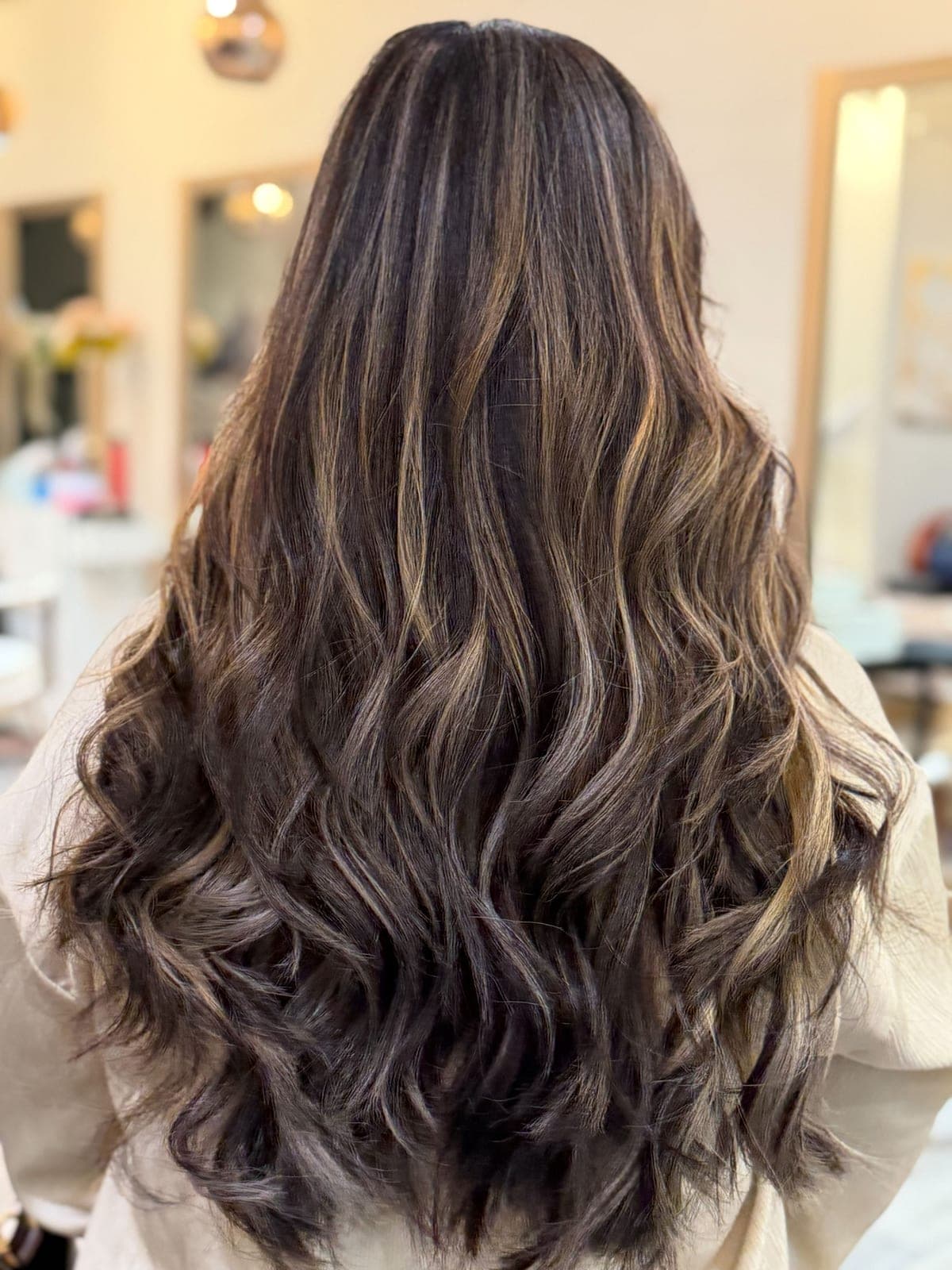 Long dark hair styled into brushed-out waves, seen from the back