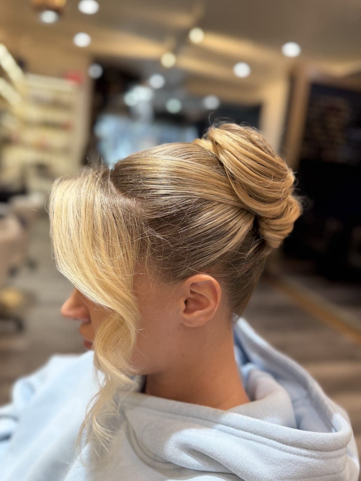 Blonde chignon updo with soft face-framing strands, seen in profile