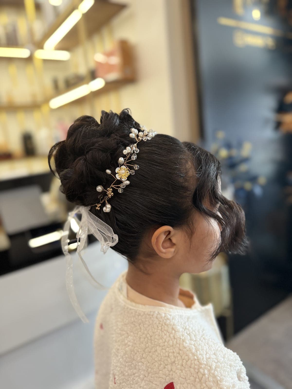 Formal updo decorated with a pearl hair vine, soft curls left at the face